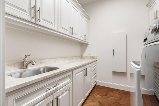 laundry room with a sink, washer / dryer, cabinet space, and wood finished floors