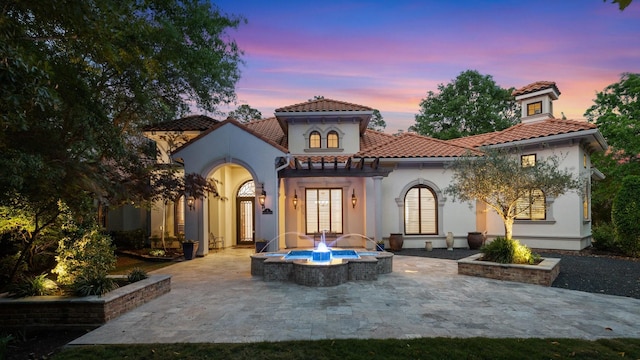rear view of property featuring a fire pit, a patio, stucco siding, french doors, and a tiled roof
