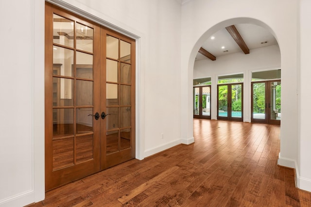 hallway featuring baseboards, beamed ceiling, french doors, and wood finished floors