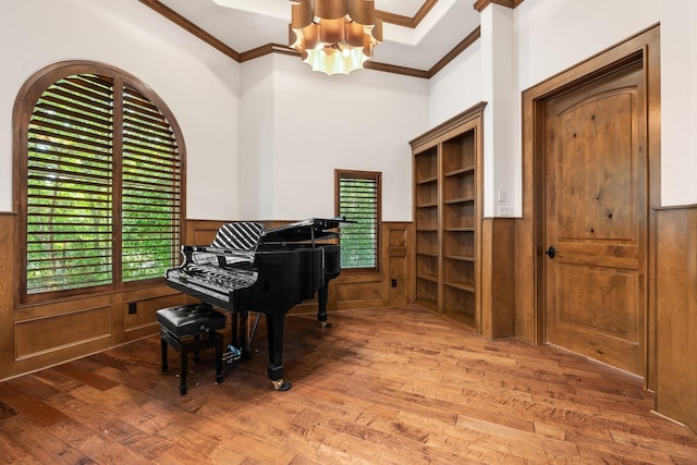 sitting room featuring an inviting chandelier, ornamental molding, wood finished floors, and a wainscoted wall