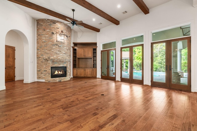 unfurnished living room with a ceiling fan, beam ceiling, french doors, and a high ceiling
