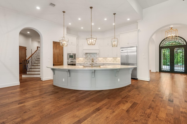 kitchen with built in appliances, backsplash, visible vents, and white cabinetry