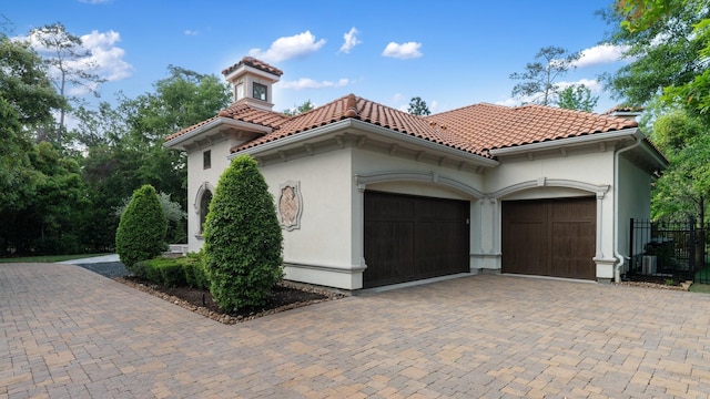 view of front of home with an attached garage, decorative driveway, stucco siding, and a tile roof