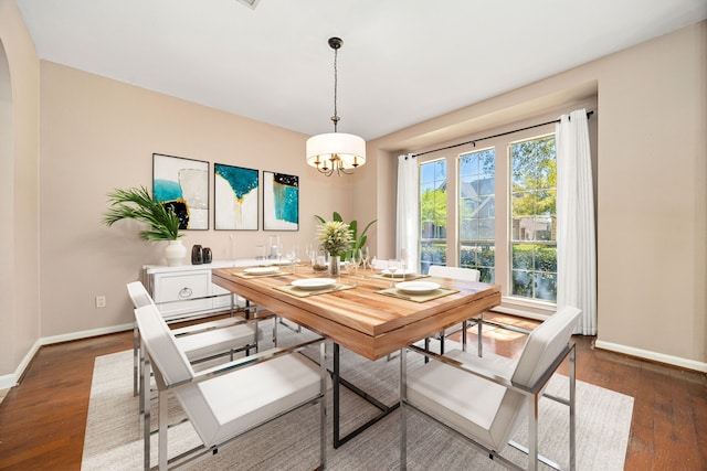 dining room featuring baseboards, arched walkways, dark wood-style floors, and a notable chandelier