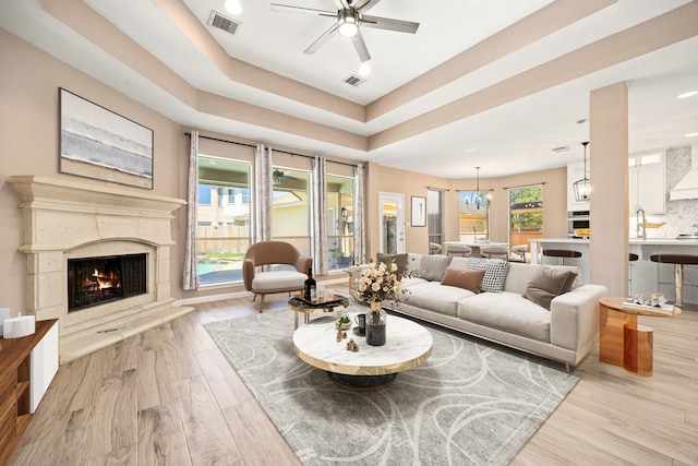 living room featuring visible vents, ceiling fan with notable chandelier, wood finished floors, and a fireplace