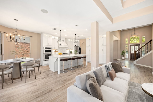 living area with an inviting chandelier, light wood-style floors, stairs, recessed lighting, and visible vents