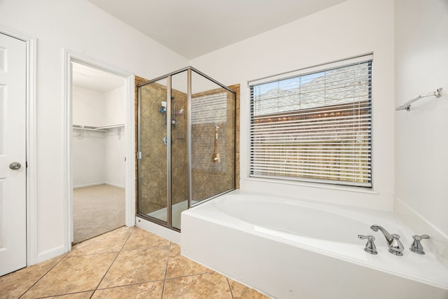 bathroom with tile patterned floors, a spacious closet, a shower stall, and a garden tub