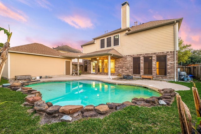 back of house at dusk with a fenced in pool, a chimney, a fenced backyard, and a patio area