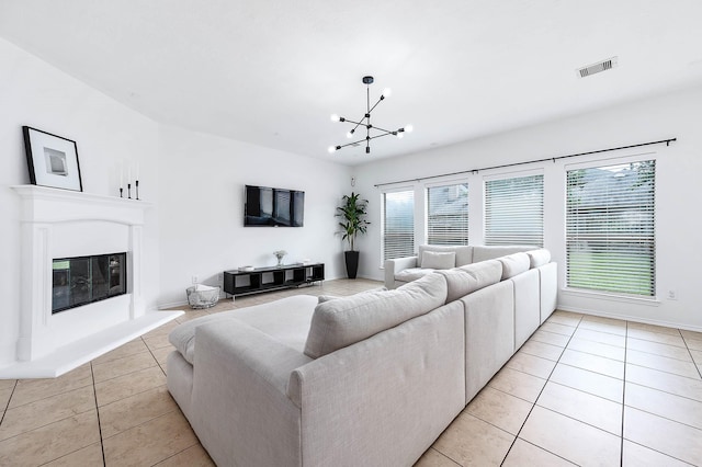 living area with light tile patterned floors, baseboards, a glass covered fireplace, visible vents, and a chandelier