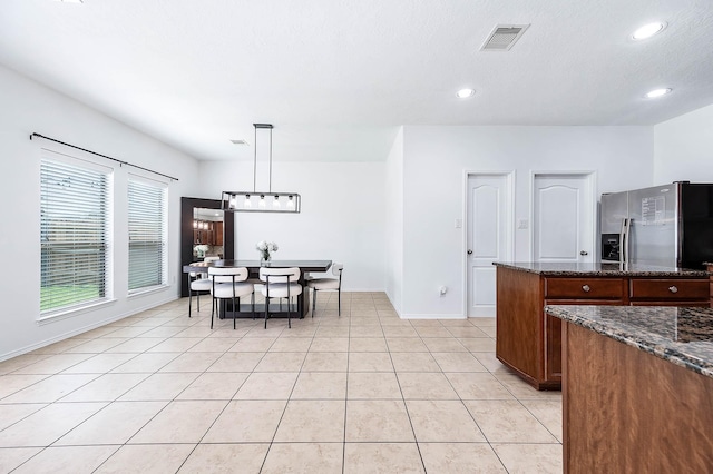 kitchen with recessed lighting, stainless steel fridge, and dark stone counters