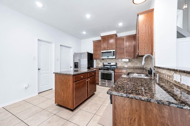 kitchen with a center island, a sink, dark stone countertops, stainless steel appliances, and tasteful backsplash