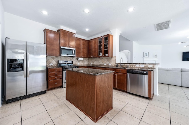 kitchen featuring visible vents, open floor plan, dark stone countertops, a kitchen island, and stainless steel appliances