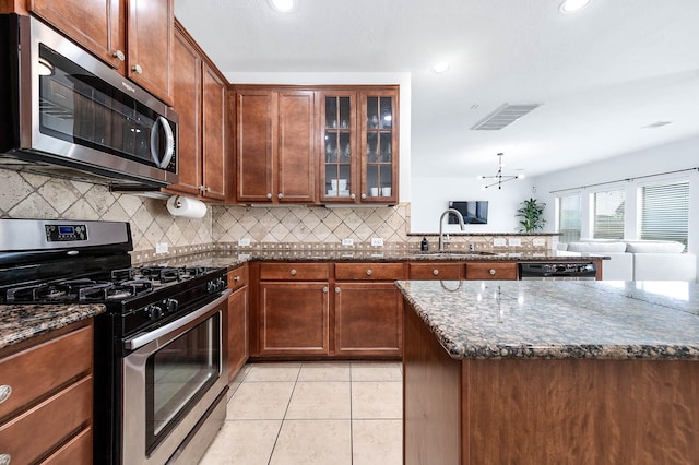 kitchen featuring visible vents, a sink, backsplash, dark stone counters, and appliances with stainless steel finishes