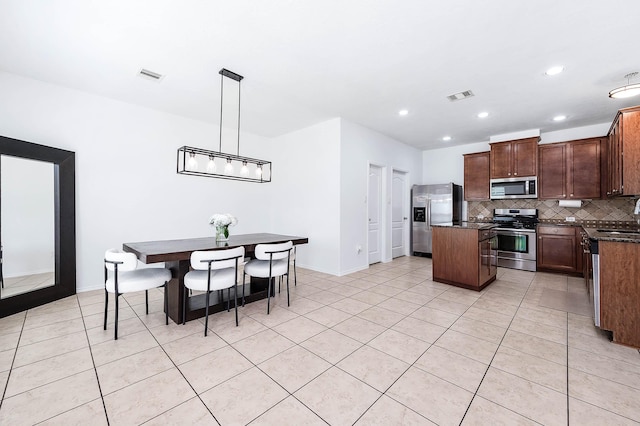 kitchen featuring light tile patterned floors, visible vents, backsplash, appliances with stainless steel finishes, and a kitchen island
