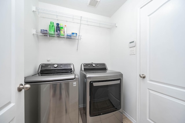 clothes washing area with washing machine and clothes dryer, tile patterned floors, laundry area, and visible vents