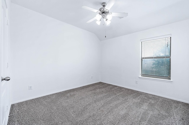 empty room featuring lofted ceiling, dark colored carpet, baseboards, and a ceiling fan