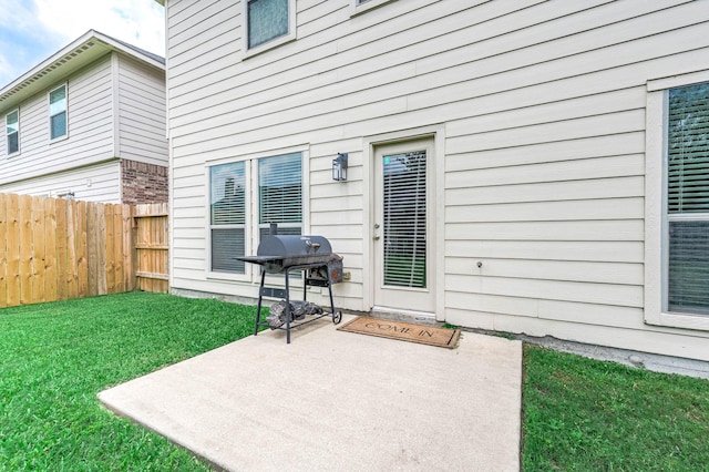 view of exterior entry with a yard, fence, and a patio