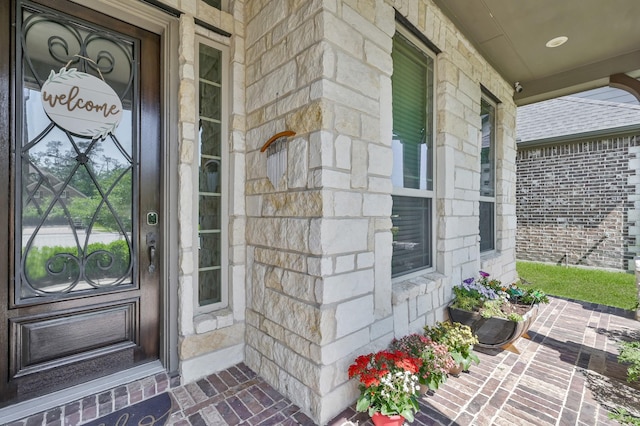 view of exterior entry with covered porch and stone siding