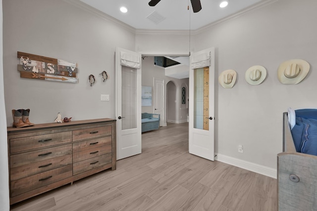 bedroom featuring arched walkways, ornamental molding, baseboards, light wood finished floors, and a ceiling fan