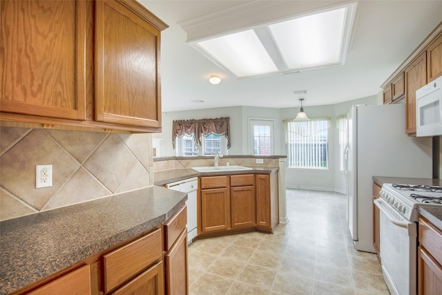 kitchen with decorative backsplash, a peninsula, white appliances, brown cabinets, and a sink