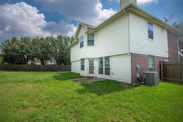 rear view of house with a lawn, central air condition unit, a chimney, and fence