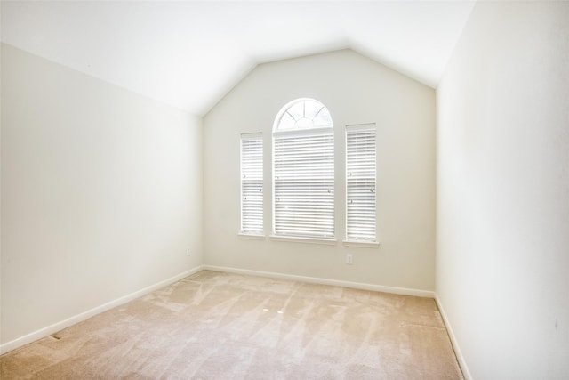 empty room featuring baseboards, light carpet, and vaulted ceiling