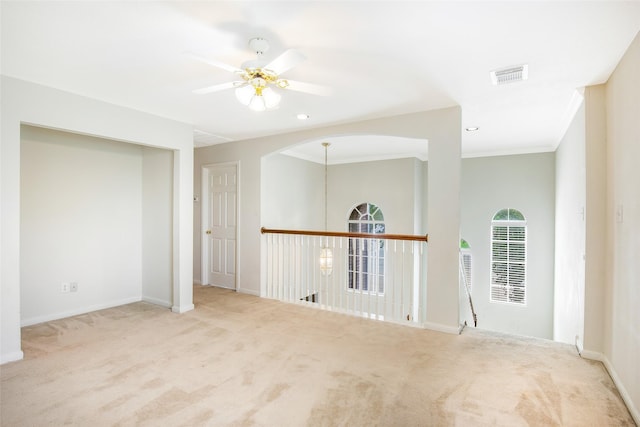 empty room with ceiling fan, carpet, baseboards, visible vents, and ornamental molding