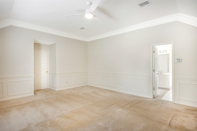 empty room with ceiling fan, visible vents, carpet floors, ornamental molding, and a decorative wall