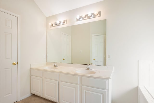 bathroom with a bath, double vanity, a sink, and lofted ceiling