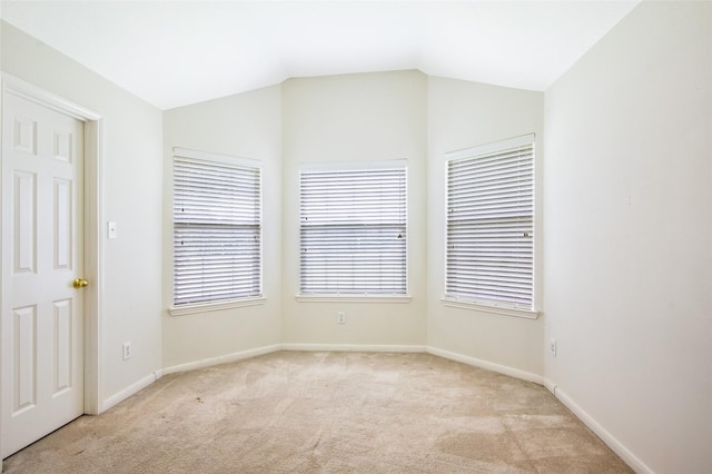 spare room with baseboards, light carpet, and lofted ceiling