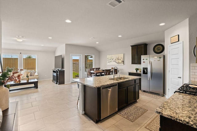 kitchen featuring visible vents, appliances with stainless steel finishes, a center island with sink, a sink, and open floor plan