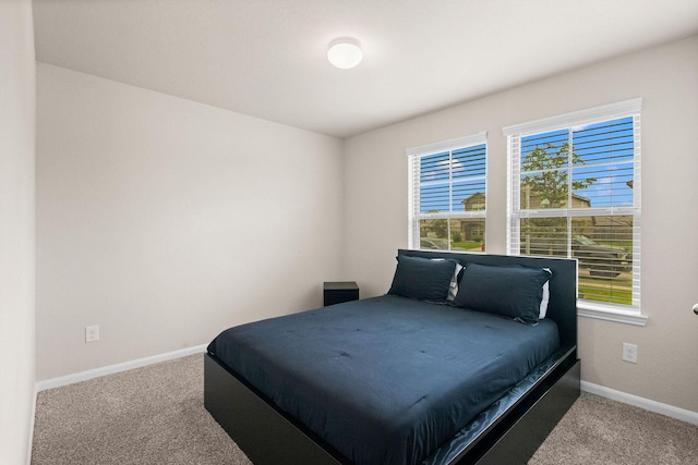 carpeted bedroom featuring baseboards and multiple windows
