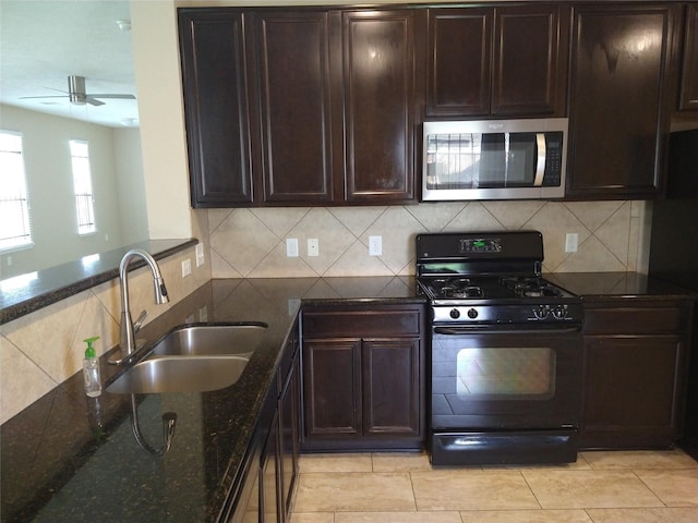 811 Sweet Flower Dr, Houston, TX 77073 - kitchen with stainless steel microwave, black gas range oven, a sink, ceiling fan, and dark stone counters
