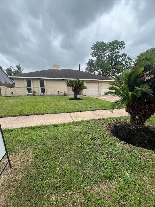 single story home with concrete driveway, a garage, and a front yard