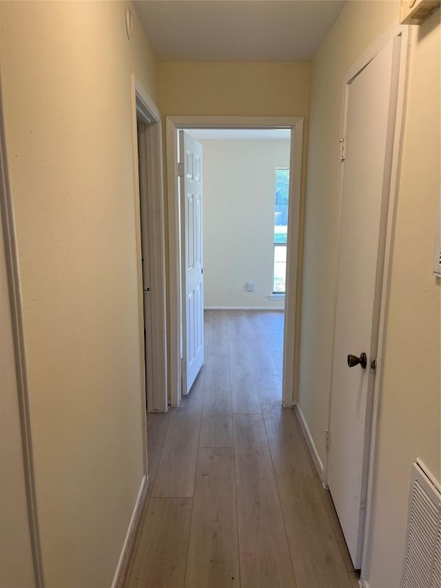 hall featuring light wood finished floors and baseboards