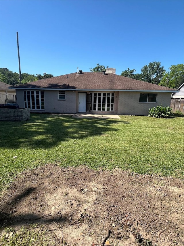 back of house with a lawn, brick siding, and a chimney
