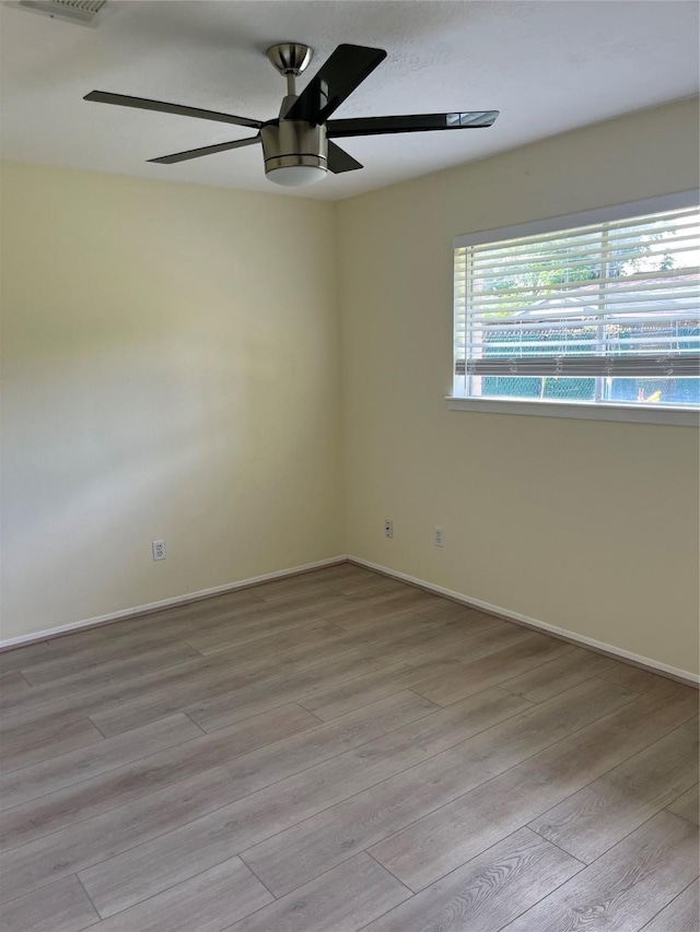 empty room with ceiling fan, light wood-type flooring, and baseboards