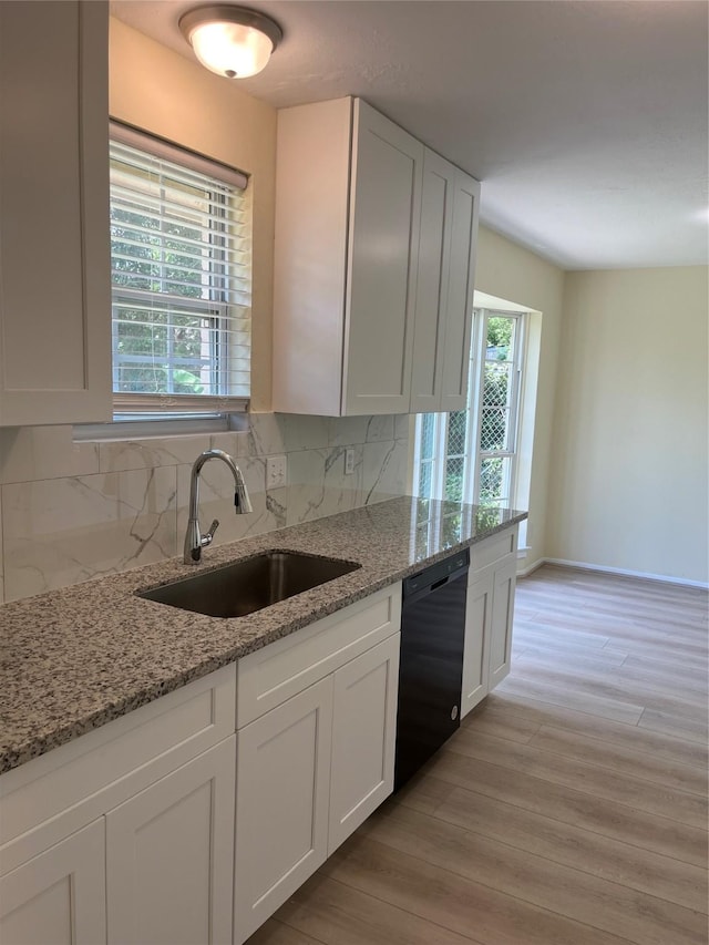 kitchen with dishwasher, a sink, white cabinets, light wood-type flooring, and backsplash