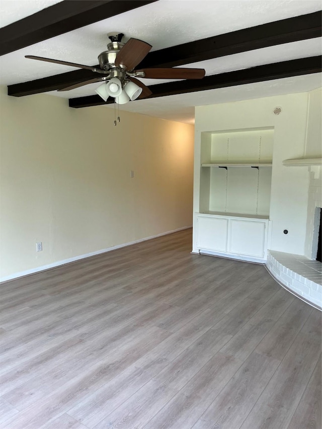 unfurnished living room with beamed ceiling, ceiling fan, light wood-type flooring, a fireplace, and baseboards