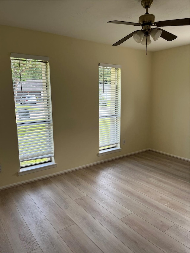 spare room featuring plenty of natural light, a ceiling fan, and wood finished floors