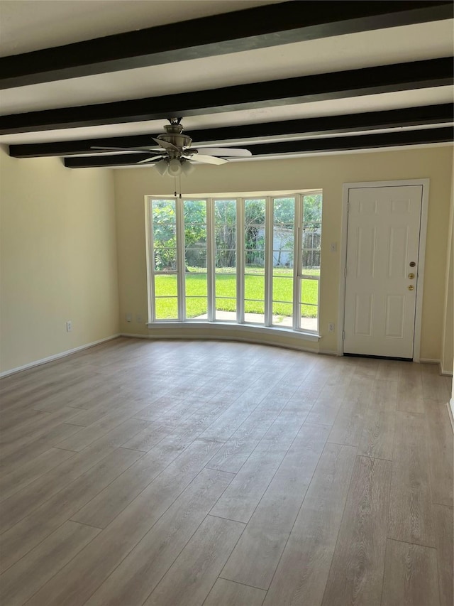 unfurnished living room with a ceiling fan, beamed ceiling, wood finished floors, and baseboards