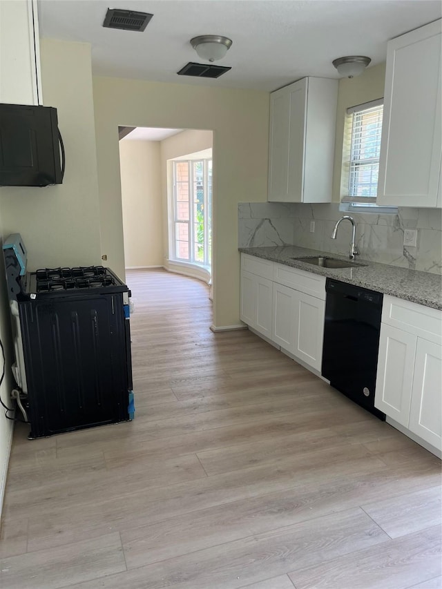 kitchen featuring black appliances, a sink, light stone countertops, and white cabinets
