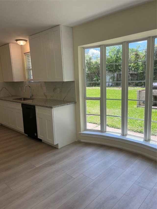kitchen featuring a sink, dishwasher, white cabinetry, decorative backsplash, and light wood-type flooring