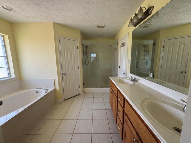 13796 County Road 318, Navasota, TX 77868 - full bath featuring a textured ceiling, a shower stall, tile patterned flooring, a bath, and double vanity