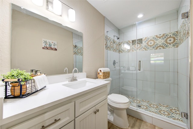 bathroom with wood finished floors, a stall shower, toilet, and vanity
