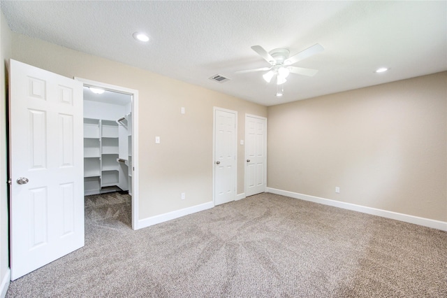 unfurnished bedroom featuring carpet floors, baseboards, visible vents, and a spacious closet