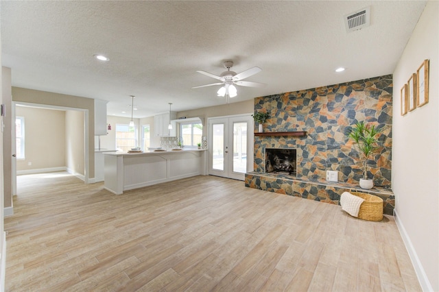 unfurnished living room with a textured ceiling, ceiling fan, light wood-style flooring, and visible vents