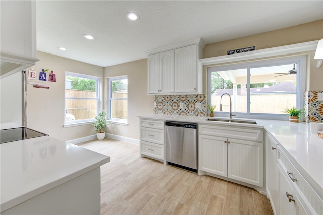 kitchen featuring light wood-type flooring, dishwasher, a sink, recessed lighting, and white cabinetry