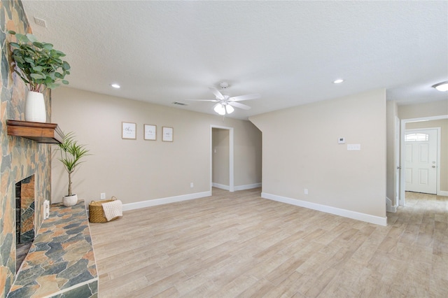 unfurnished living room with light wood-style floors, a stone fireplace, a ceiling fan, recessed lighting, and visible vents