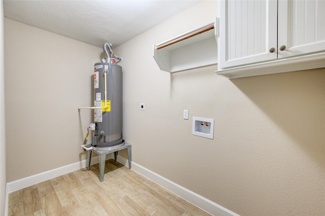 laundry area featuring baseboards, cabinet space, gas water heater, electric dryer hookup, and light wood-style flooring